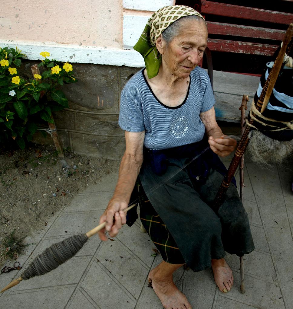 p7240905.jpg - nénike fonja a fonalat a kapu előtt üldögélve.